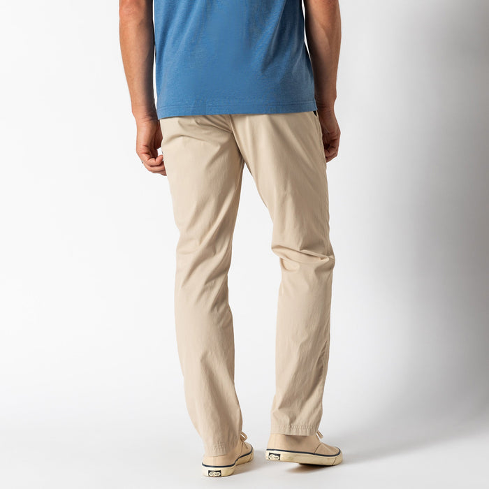 Light beige chino pants worn with blue shirt, back three-quarter view showing fit and silhouette