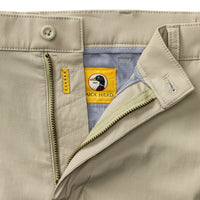 Light tan chino pants with open fly showing striped interior lining and branded waistband detail