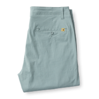 Light green chino pants folded flat showing back pocket with button closure and small logo tab