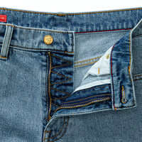 Close-up of light blue denim jeans showing waistband, button closure, and front zipper detail