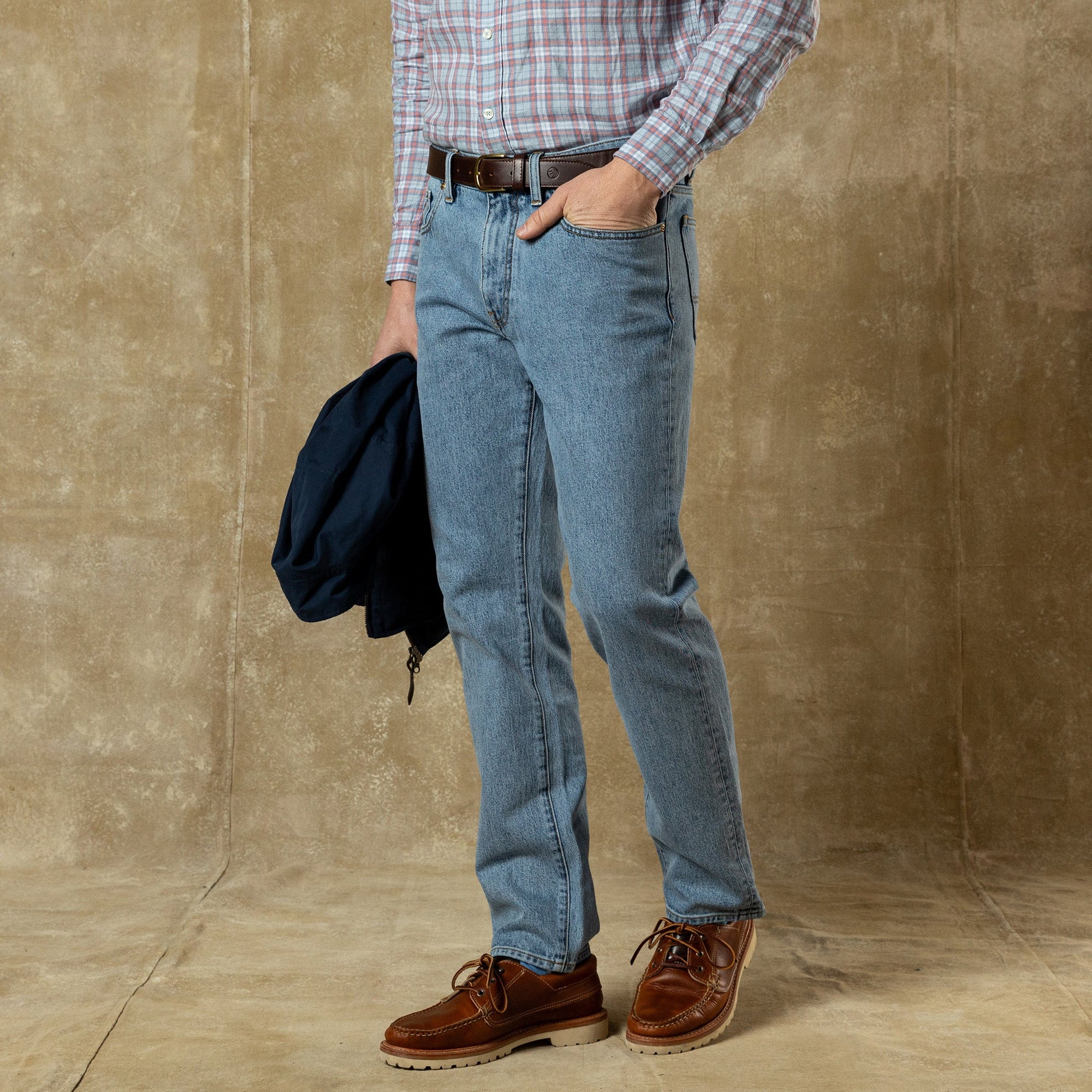 Men's straight fit light blue denim jeans styled with plaid shirt and brown boots