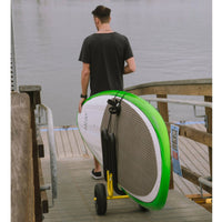 Wheeled cart holding paddleboard on wooden dock with person walking away