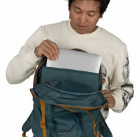 Person placing a laptop into the padded laptop sleeve of an open daypack backpack