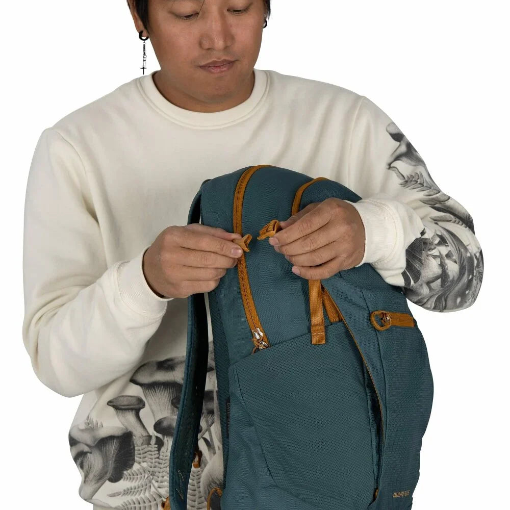 Person opening a teal backpack, showing zipper pulls and top handle detail close-up