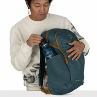 Person placing a branded water bottle into the side pocket of a daypack
