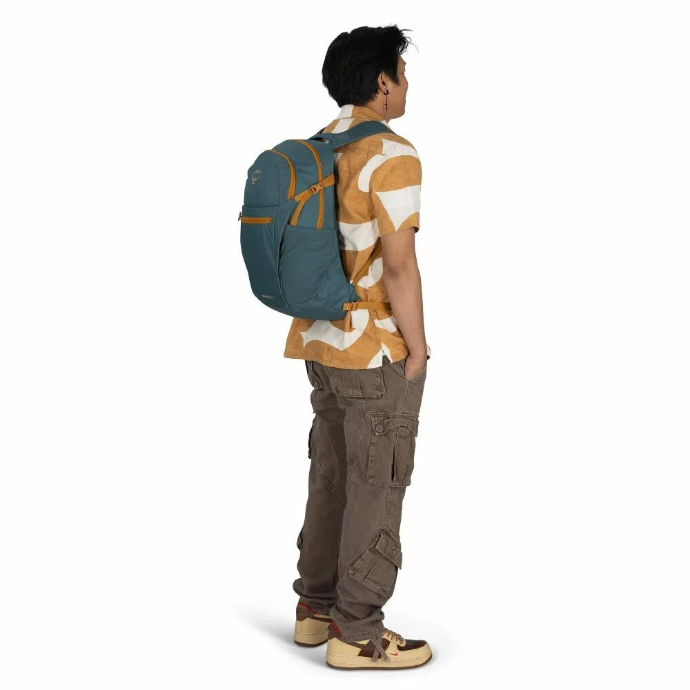 On-body back view of a medium daypack with teal fabric and tan accent straps, worn by a model