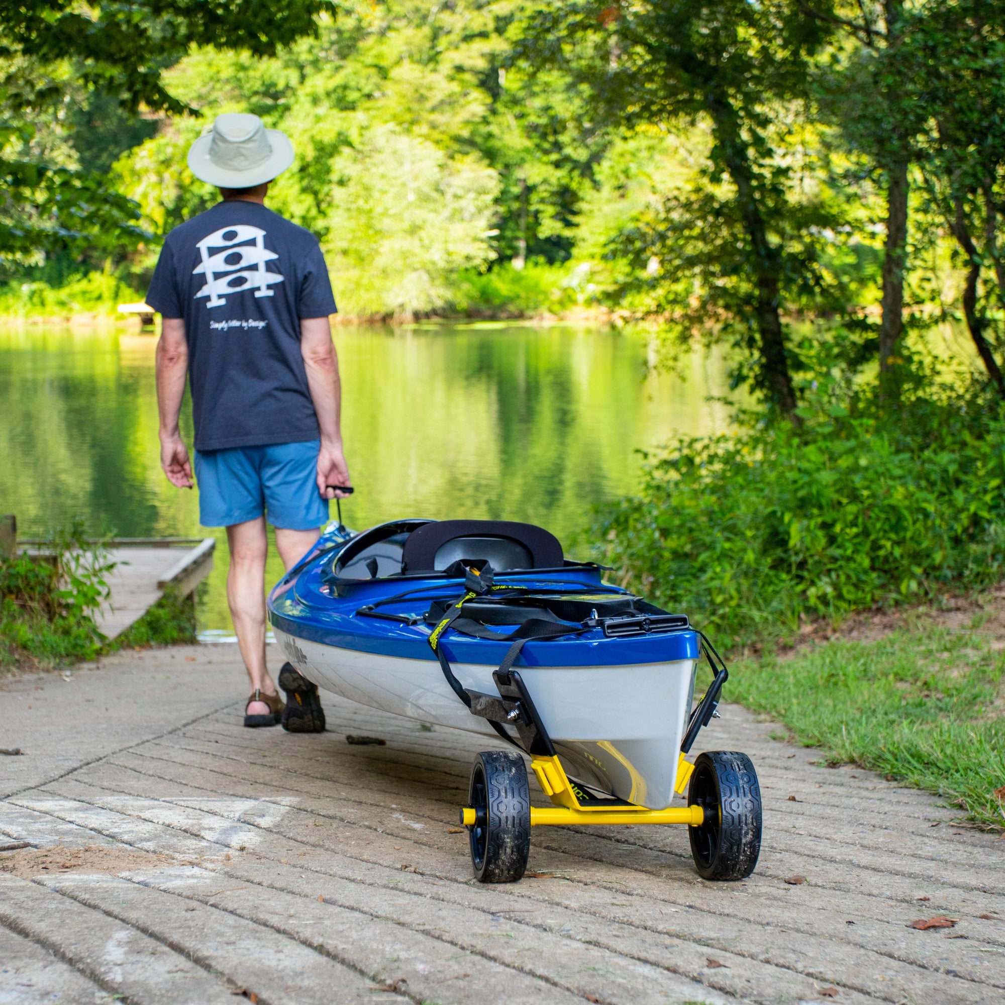 Yellow kayak cart with wheels supporting blue kayak on concrete path near lake