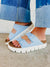 Light blue platform sandals with two adjustable straps and chunky white sole worn with jeans