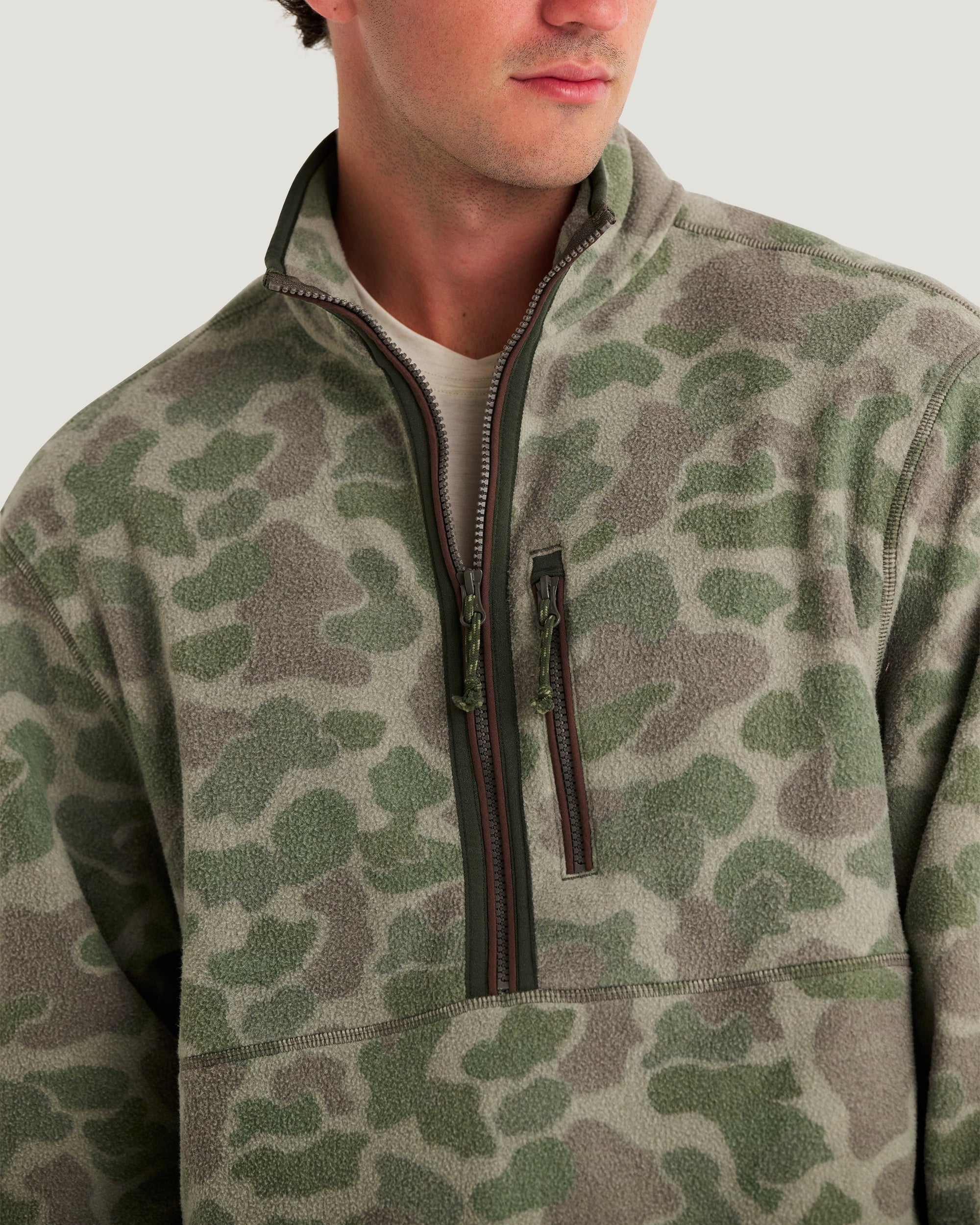 Men's camo fleece half-zip pullover with chest pocket and rope zipper pulls, close-up detail view