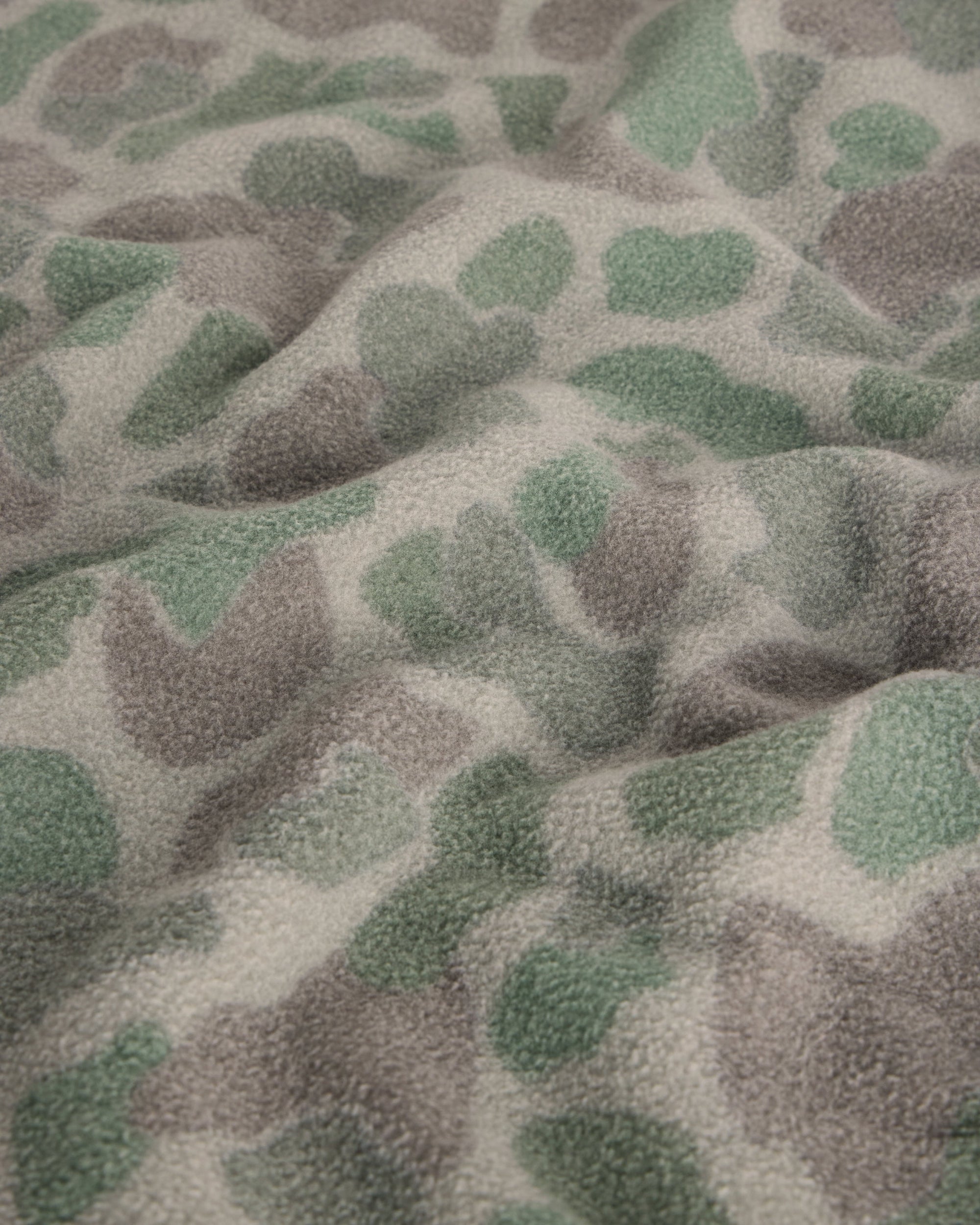 Close-up detail of fleece fabric with green and gray camouflage spot pattern
