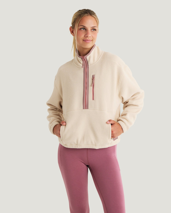 Women's cream fleece half-zip pullover with pink zipper, front view on model