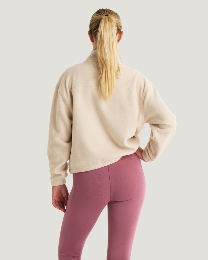 Women's cropped fleece half-zip pullover in cream, back view on model with ponytail
