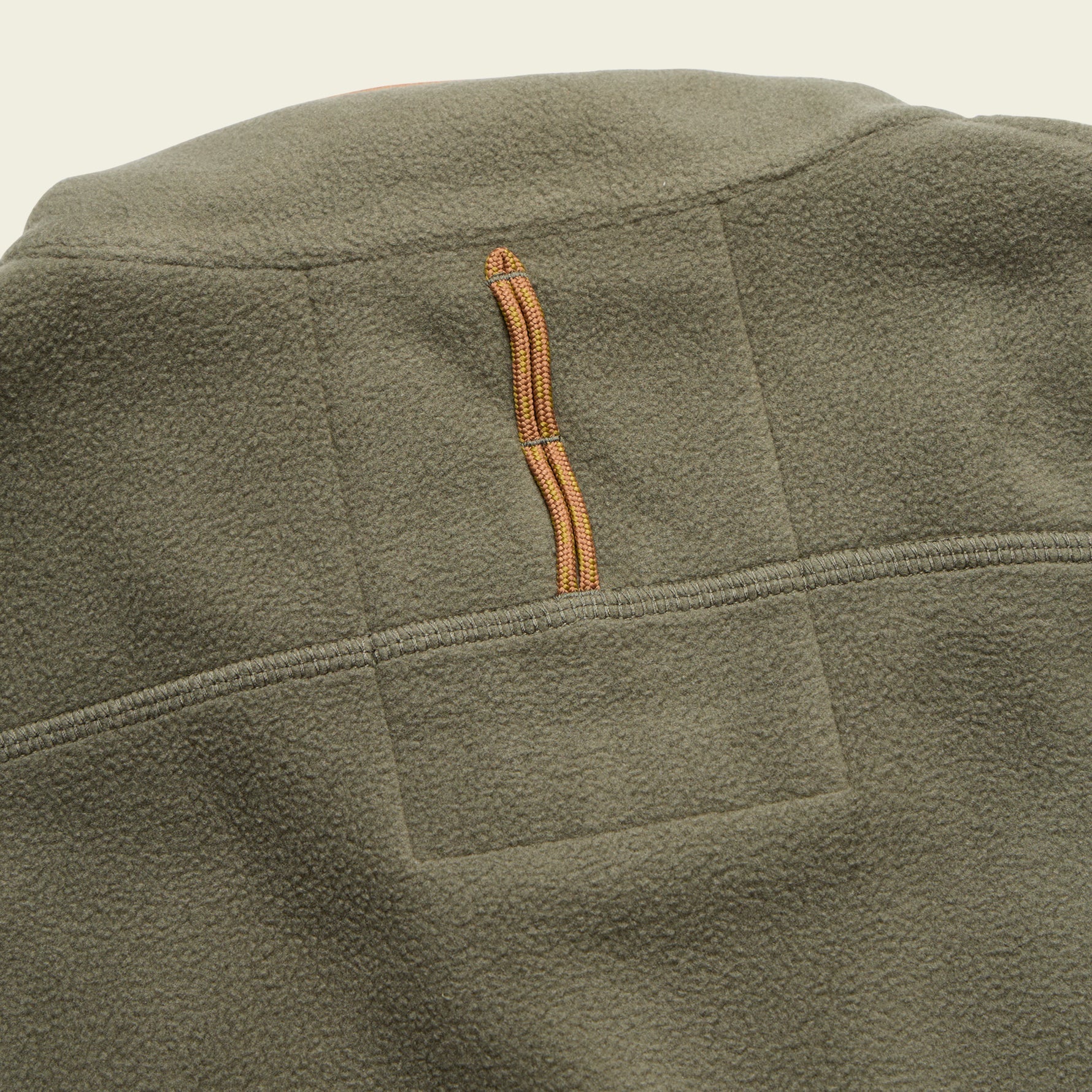 Close-up detail of olive green fleece vest showing quilted back panel and orange zipper pull