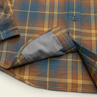 Close-up detail of plaid flannel shirt hem and interior pocket lining with snap button