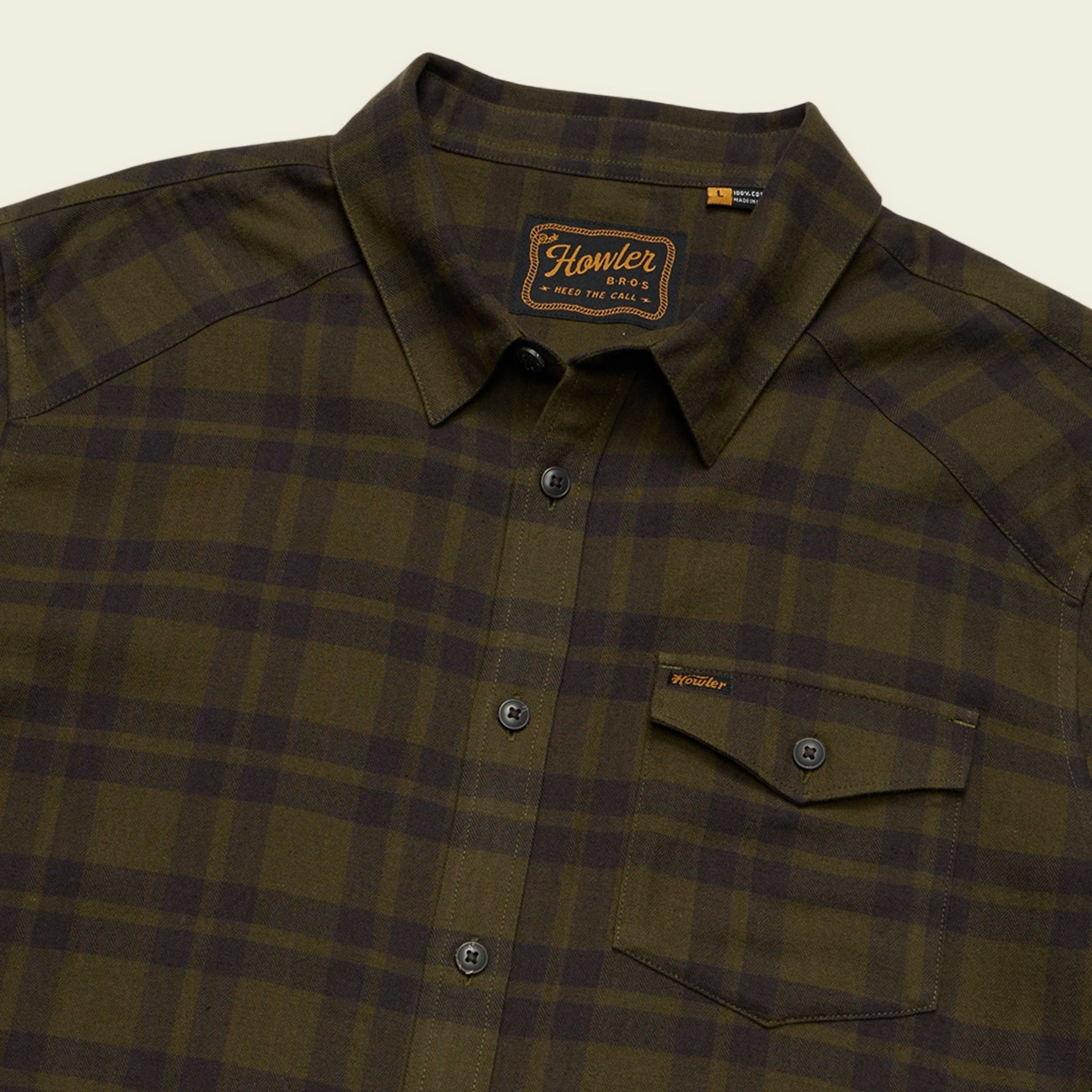 Men's plaid flannel shirt in dark olive, close-up of collar and chest pocket with brand label