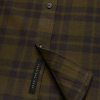 Close-up detail of plaid flannel shirt showing buttons, placket, and interior label