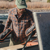 Man loading gear into a river boat wearing a plaid lightweight flannel shirt, lifestyle shot