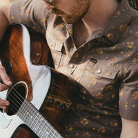 Men's floral snap-button western shirt with chest pockets, shown on model playing acoustic guitar