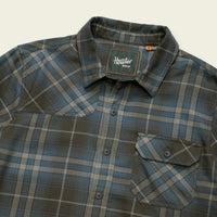 Men's plaid flannel shirt detail shot showing collar, snap buttons, and chest pocket
