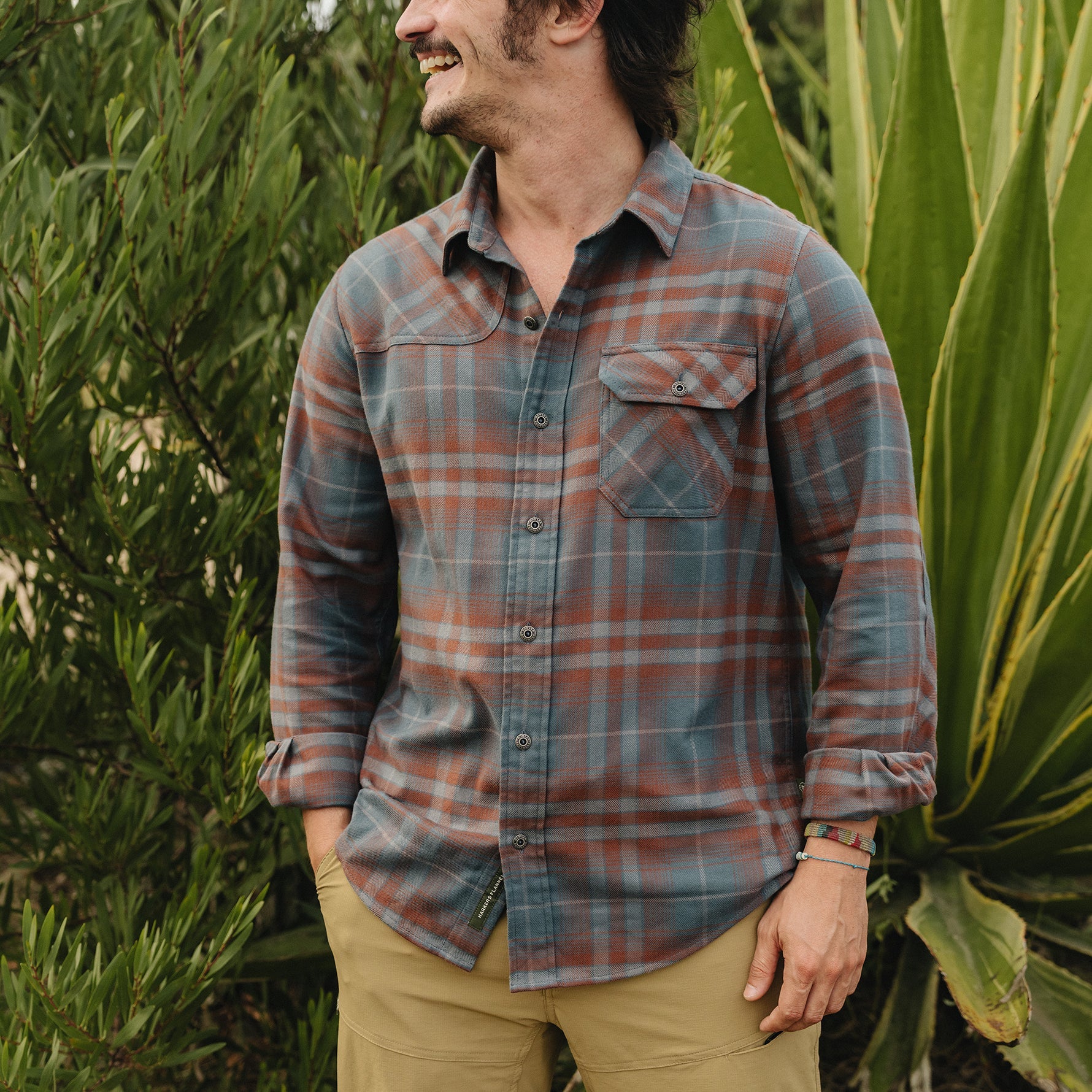 Men's plaid flannel shirt in blue-gray and rust tones, on-model lifestyle shot, front view