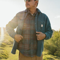 Men's plaid flannel shirt worn open over white tee, outdoor lifestyle shot at golden hour