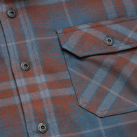 Close-up detail of plaid flannel shirt chest pocket with branded snap buttons