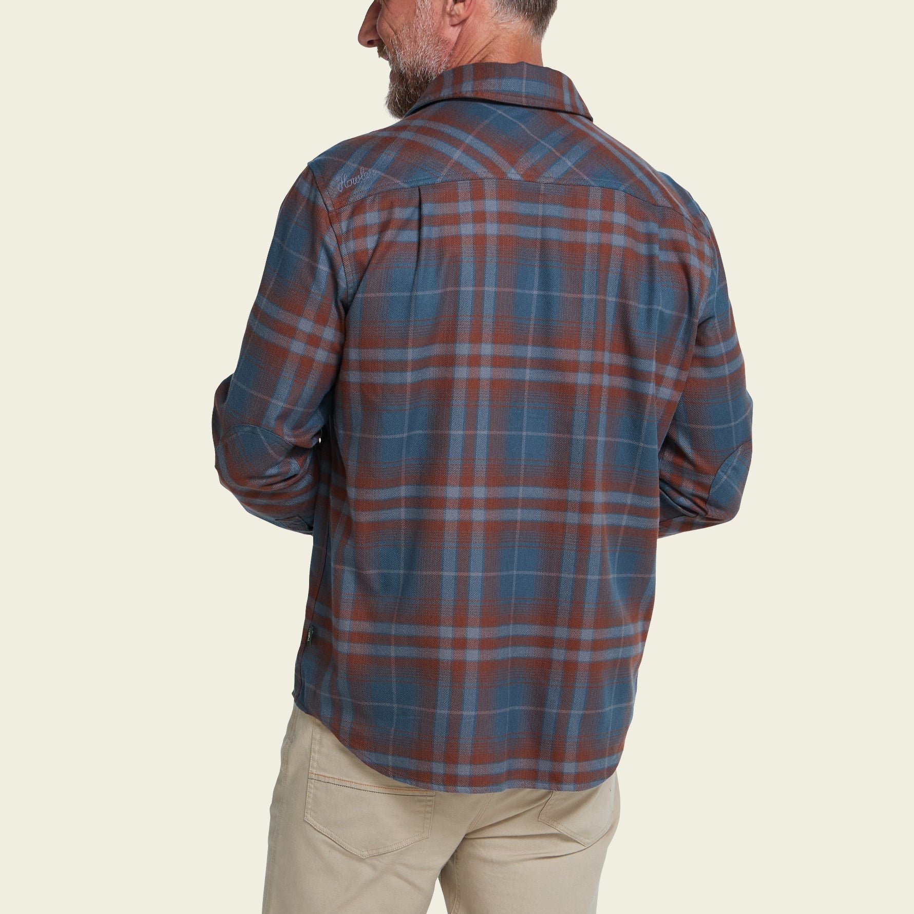 Men's plaid flannel shirt in dark slate and rust tones, back view, long sleeves rolled at cuff
