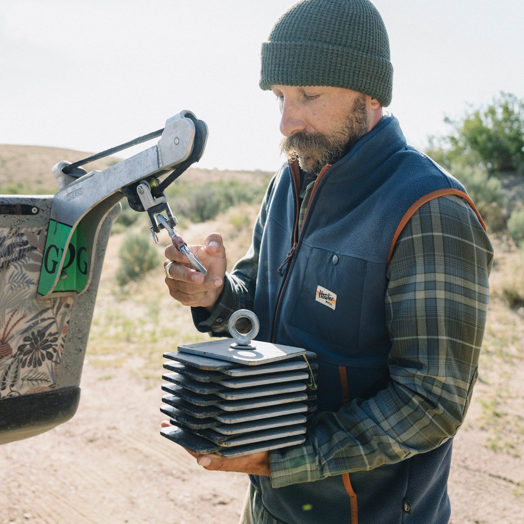 Man wearing a dark navy fleece vest over plaid shirt in outdoor desert setting