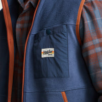 Close-up detail of men's fleece vest chest pocket with brand patch label and snap closure