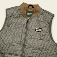 Quilted sleeveless vest with diagonal stitch pattern, zip front, ribbed collar, and logo patch