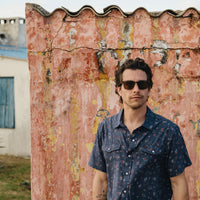 Men's short-sleeve snap button shirt in dark navy floral print, worn on model outdoors