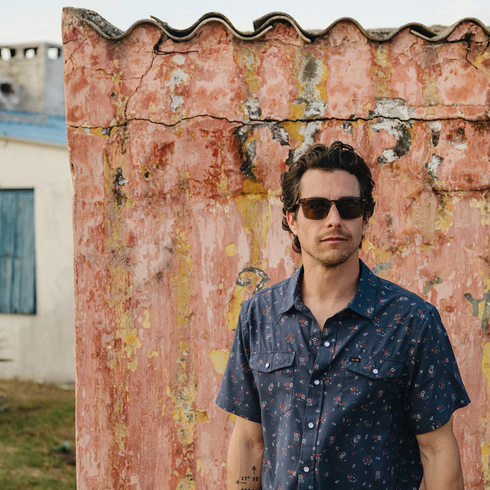 Men's short-sleeve snap button shirt in dark navy floral print, worn on model outdoors