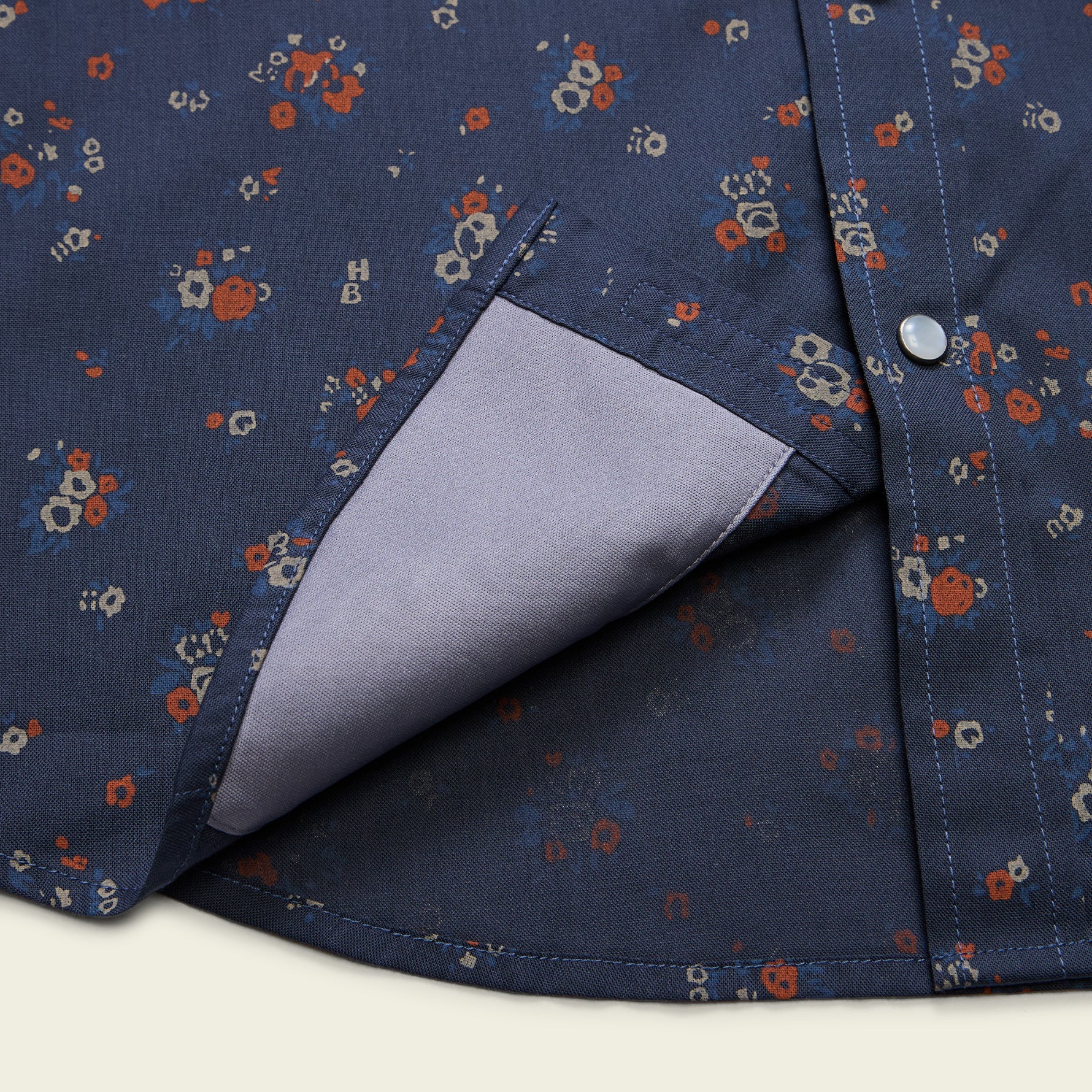 Close-up detail of floral print snap shirt pocket with contrast lining revealed