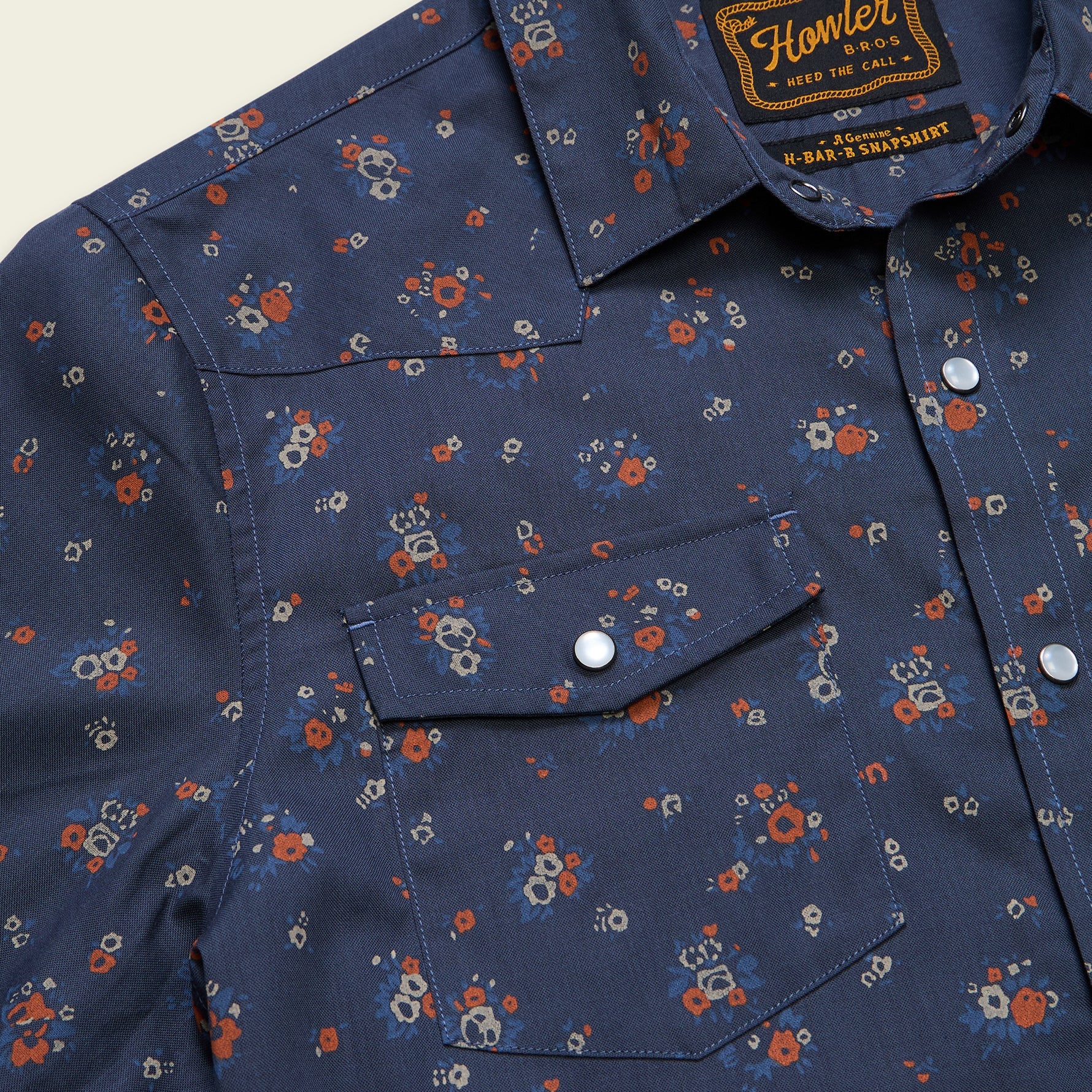 Close-up detail of a navy floral western snap shirt with dual chest pockets and silver snaps