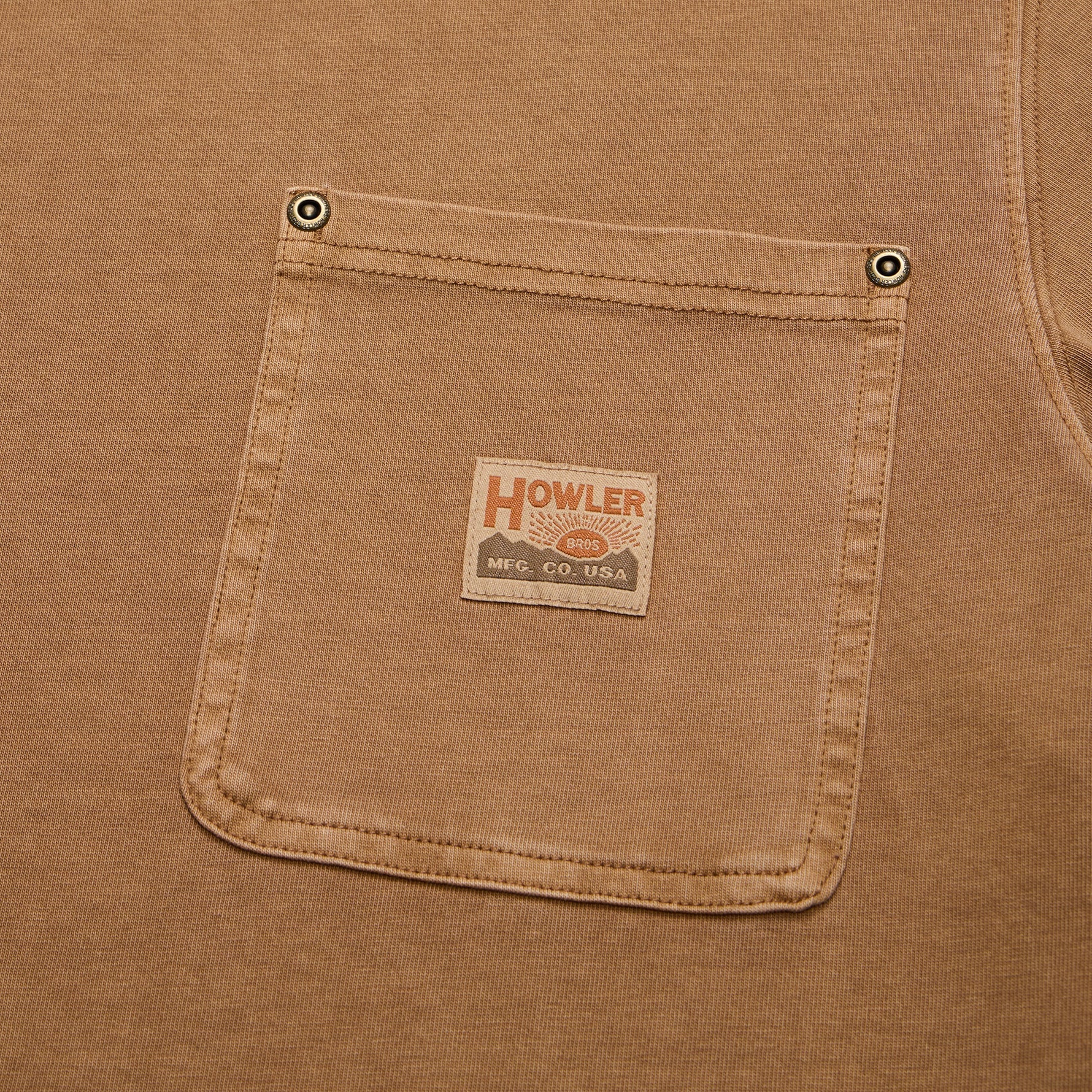 Close-up detail of chest pocket on cotton t-shirt with metal rivets and woven brand patch