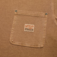 Close-up detail of chest pocket on cotton t-shirt with metal rivets and woven brand patch
