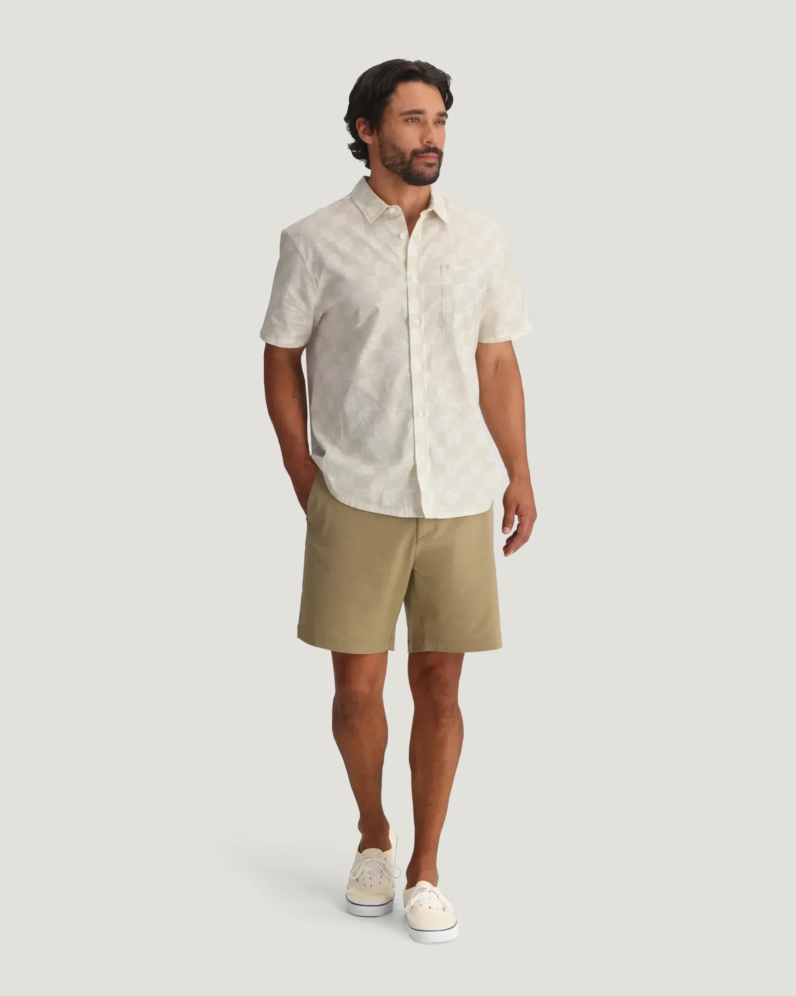 Light colored short sleeve button-up shirt with subtle shell print pattern worn with khaki shorts