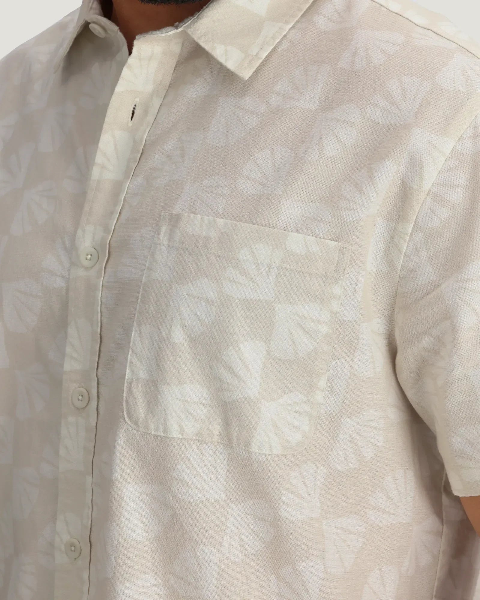 Light colored linen button-up shirt with chest pocket and subtle shell print pattern