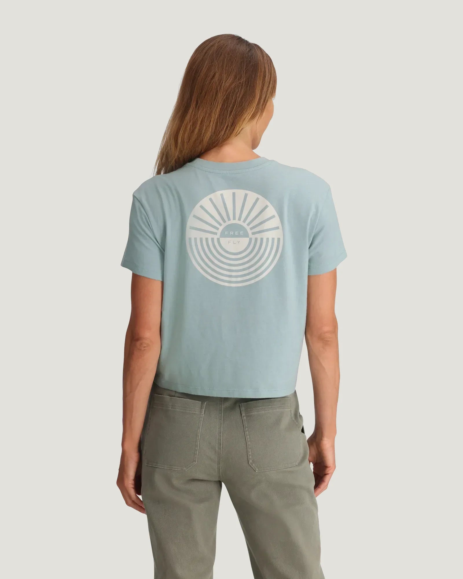 Light blue cropped t-shirt with circular sun and wave graphic on back, rear view