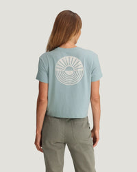 Light blue cropped t-shirt with circular sun and wave graphic on back, rear view