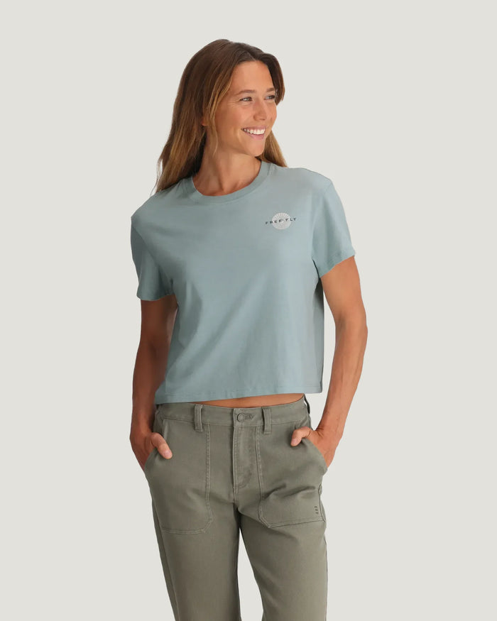 Light blue short-sleeve cropped t-shirt on woman with hands in pockets, front view