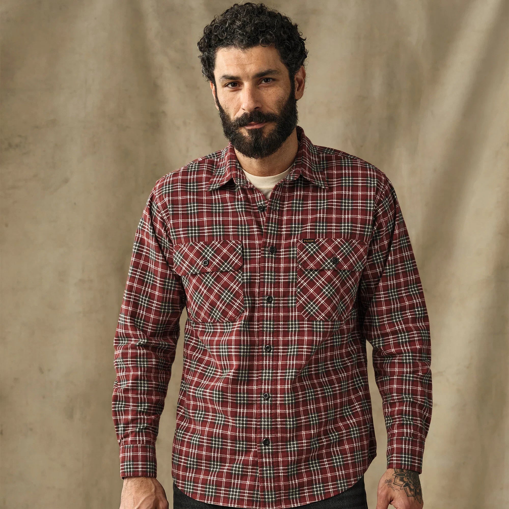 Men's plaid flannel shirt in red tartan pattern with dual chest pockets, front view on model