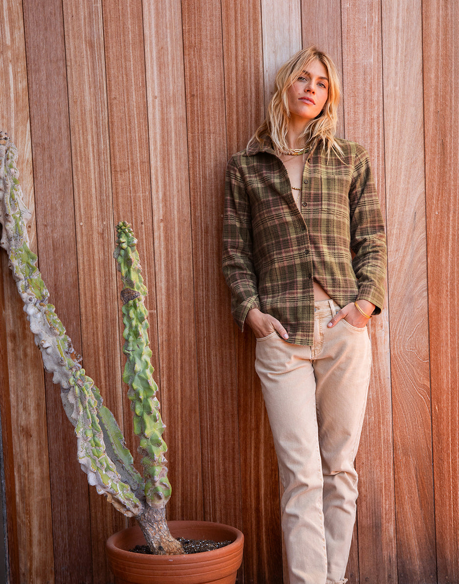 Women's plaid flannel button-up shirt in olive tones, worn open over neutral top, front view