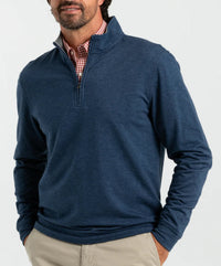 Man wearing heathered navy quarter-zip pullover over red checkered shirt with khaki pants