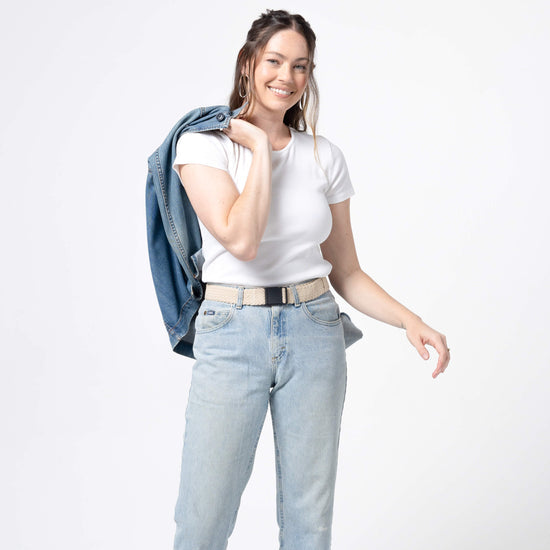Woman wearing tan colored belt with light jeans and white t-shirt, studio lighting