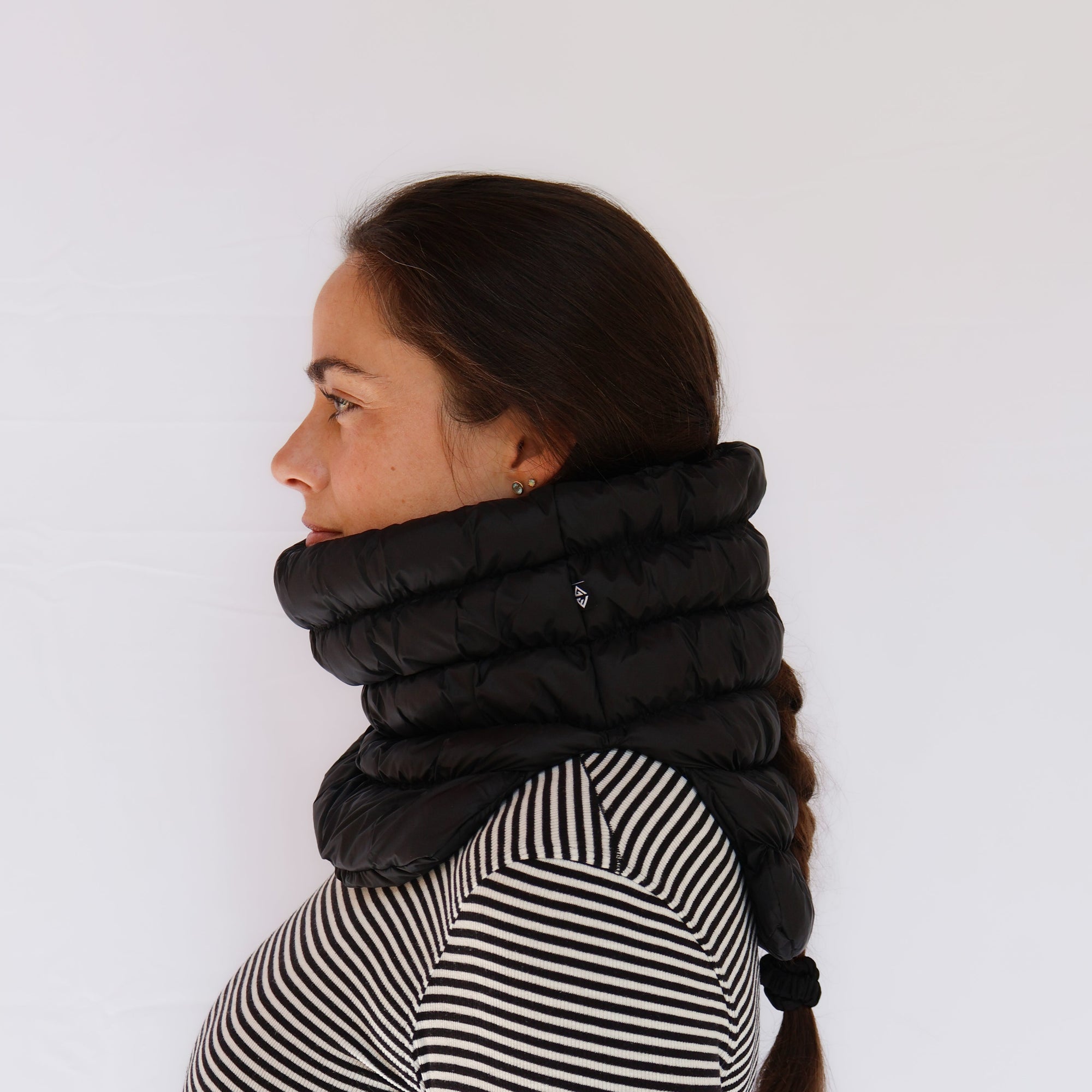 Black quilted puffer neck gaiter worn by model, side profile view showing full coverage