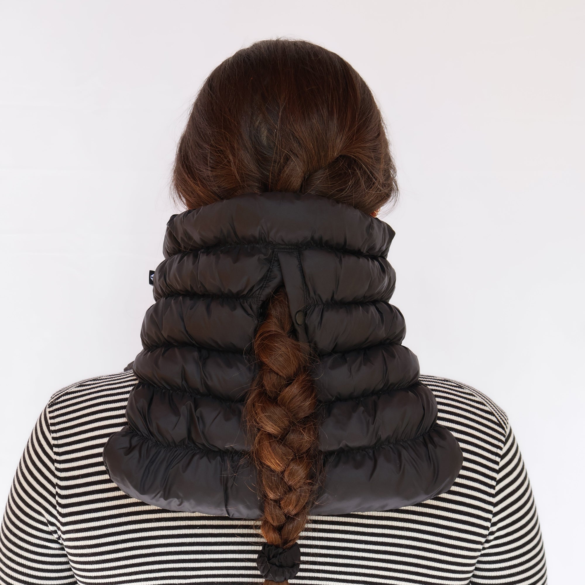 Black quilted puffer neck gaiter worn by model, back view showing braid