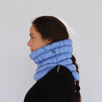 Puffer-style quilted neck gaiter in light blue worn by a model, side profile view