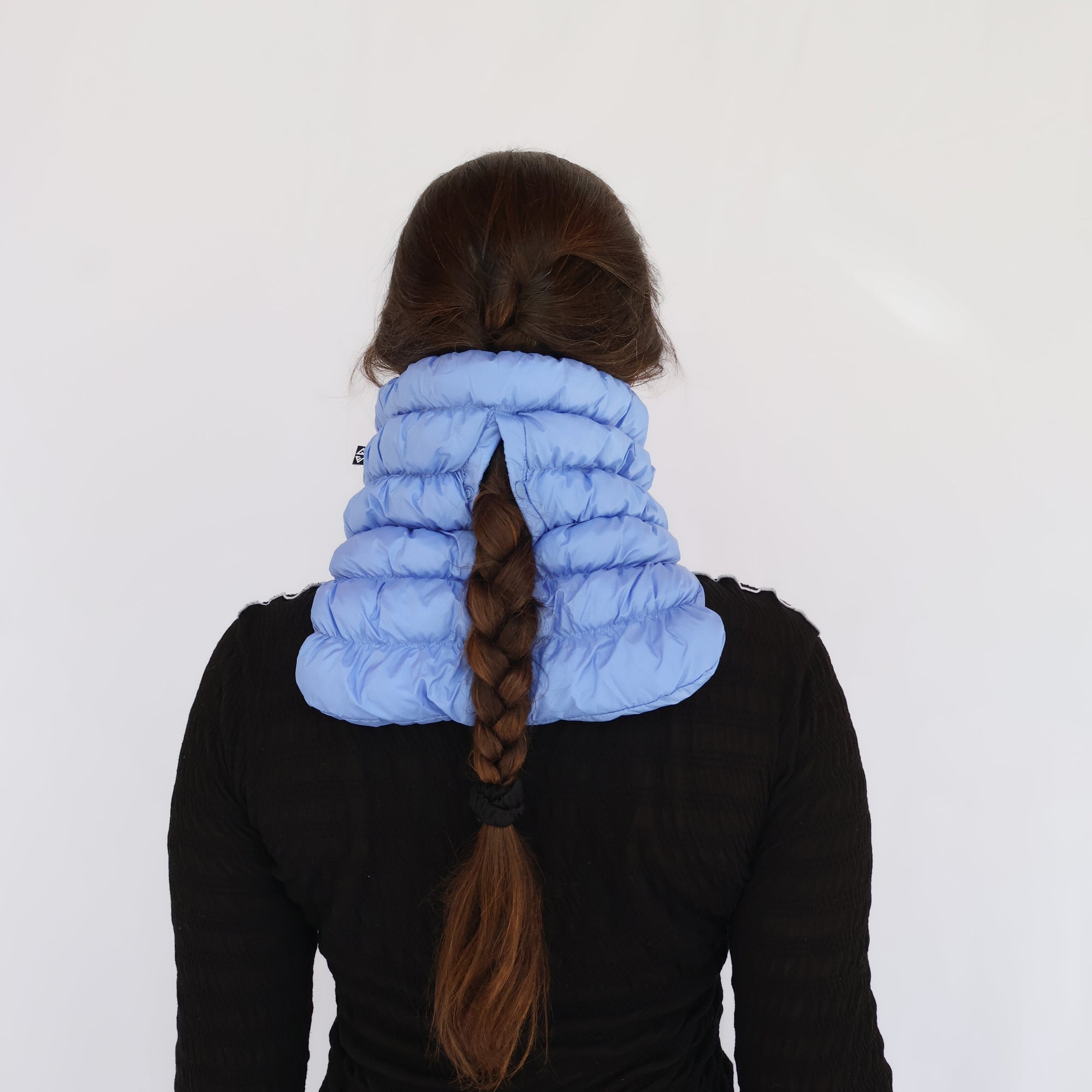Puffy quilted neck gaiter in light blue worn by model, back view showing braid