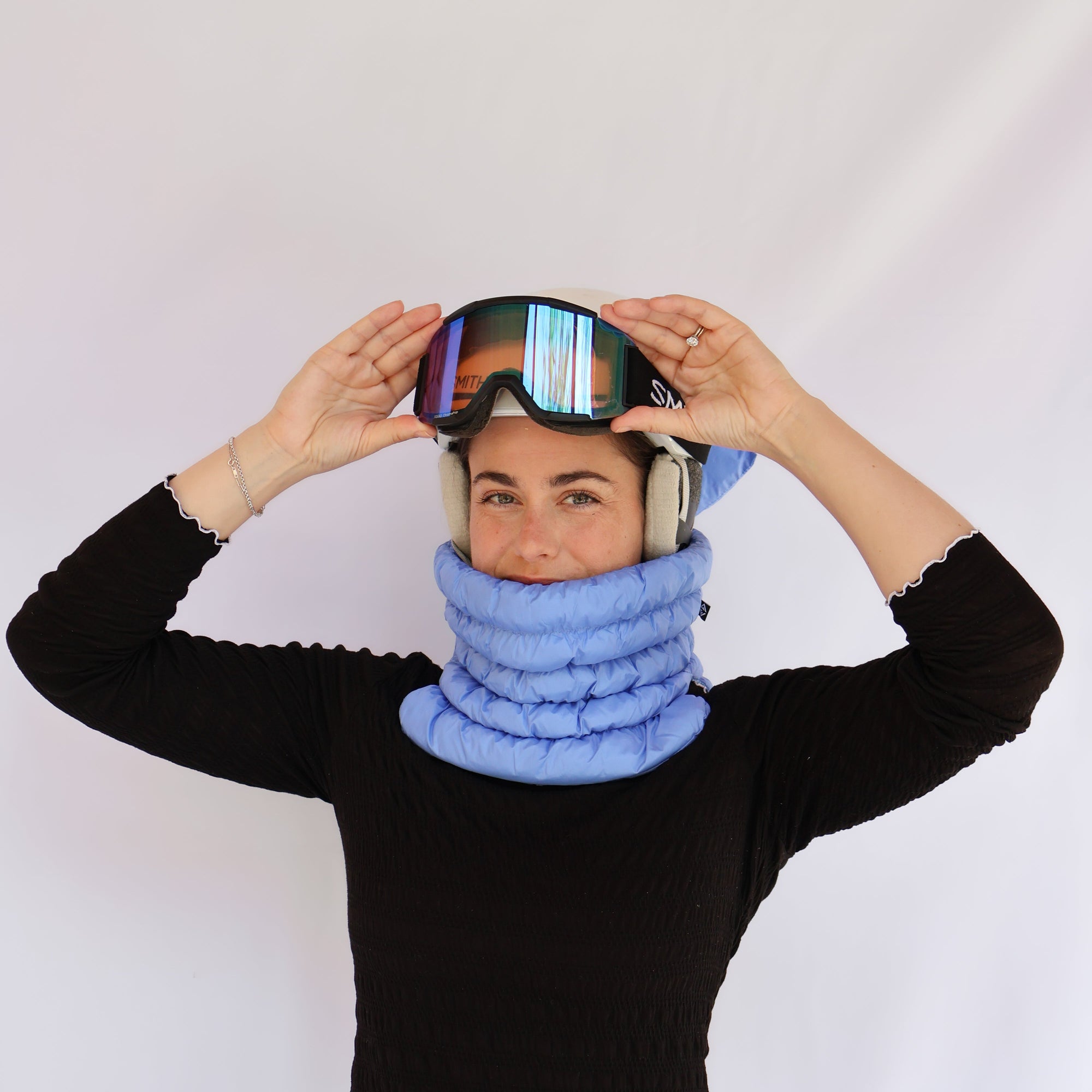 Model wearing a quilted puffer neck gaiter with ski goggles and helmet, front view